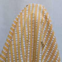 Load image into Gallery viewer, Flat lay of Joy cotton seersucker in mango colourway. Available at Minerva's Bower. Fabric draped to show how it handles