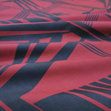 Load image into Gallery viewer, Metropolis is a dramatic, large scale graphic print. Pure cotton, with black on a claret red background, available at Minerva's Bower. Fabric is draped across bench