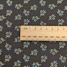 Load image into Gallery viewer, Close up of Japanese cotton fabric with a small floral pattern on a black base, with ruler included for scale, for sale at Minerva's Bower