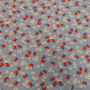 Flat lay of fabric with red apples and white flowers on a blue background in a vintage style, for sale at Minerva's Bower