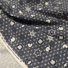 Load image into Gallery viewer, Pattern of cat faces and text on a dark  blue background of cotton dobby fabric. Made in Japan. Available at Minerva's Bower. Fabric draped to show how it handles