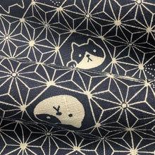 Load image into Gallery viewer, Pattern of cat faces and text on a dark  blue background of cotton dobby fabric. Made in Japan. Available at Minerva's Bower. Fabric draped to show how it handles