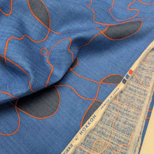 Load image into Gallery viewer, Abstract pattern with orange and black lines on a blue background of cotton dobby fabric. Available at Minerva's Bower. Fabric draped to show how it handles