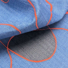 Load image into Gallery viewer, Abstract pattern with orange and black lines on a blue background of cotton dobby fabric. Available at Minerva's Bower. Fabric draped to show how it handles