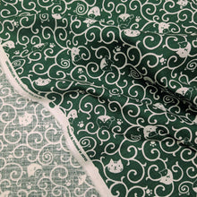 Load image into Gallery viewer, Pattern of white cats and swirls on a green cotton dobby background. Made in Japan. Available at Minerva's Bower. Fabric draped to show how it handles