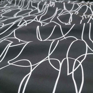 Klee is a stunning pure cotton with continuous, large scale, line drawings. White lines on a black background, available at Minerva's Bower. Fabric is draped across bench