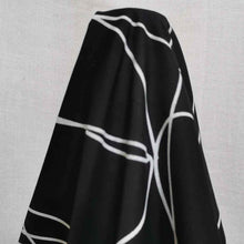 Load image into Gallery viewer, Klee is a stunning pure cotton with continuous, large scale, line drawings. White lines on a black background, available at Minerva&#39;s Bower. Fabric is draped over roll