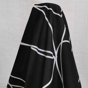 Klee is a stunning pure cotton with continuous, large scale, line drawings. White lines on a black background, available at Minerva's Bower. Fabric is draped over roll