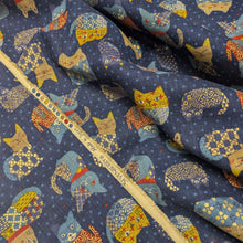 Load image into Gallery viewer, Pattern of colourful cats on a blue cotton dobby background. Made in Japan. Available at Minerva's Bower. Fabric draped to show how it handles