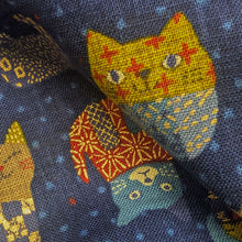 Load image into Gallery viewer, Pattern of colourful cats on a blue cotton dobby background. Made in Japan. Available at Minerva's Bower. Fabric draped to show how it handles