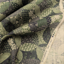 Load image into Gallery viewer, Patterned cotton fabric with green and black circles and shapes. Made in Japan. Available at Minerva's Bower. Fabric draped to show how it handles