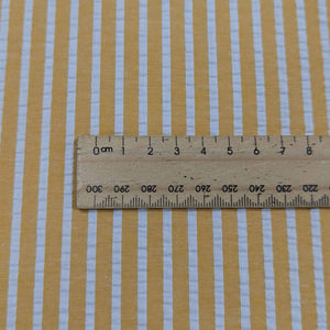 Flat lay of Joy cotton seersucker in mango colourway. Available at Minerva's Bower. Ruler included for scale