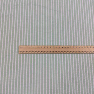 Flat lay of Joy cotton seersucker in mint colourway. Available at Minerva's Bower. Ruler included to show scale