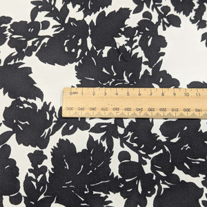 Close up of Black floral pattern cotton twill fabric with a white background, for sale at Minerva's Bower, ruler included for scale