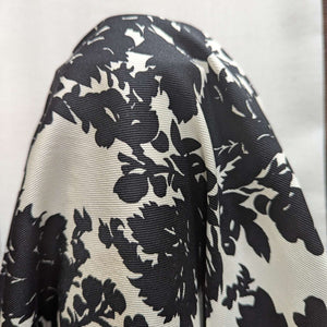 Close up of draped Black floral pattern cotton twill fabric with a white background, for sale at Minerva's Bower