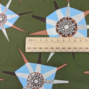 Liberty of London fabric with geometric pattern and ruler for scale on a green background. Available at Minerva's Bower
