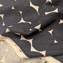 Load image into Gallery viewer, Pattern of black circles on a beige cotton/linen fabric background. Made in Japan. Available at Minerva's Bower. Fabric draped to show how it handles