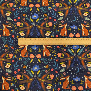 Patterned Art Gallery cotton fabric with foxes, rabbits, and flowers on a dark blue background, with a ruler for scale.