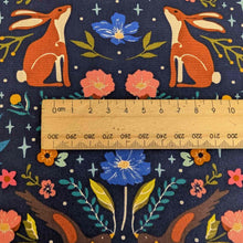 Load image into Gallery viewer, Close up of Art Gallery cotton Fabric with hares and flowers pattern and a ruler for scale on a dark blue background