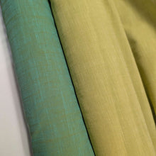 Load image into Gallery viewer, Solid green colour cotton fabricswatch with a textured pattern. Available at Minerva's Bower. Fabric draped to show how it handles. Different colourways lay side by side