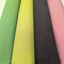 Load image into Gallery viewer, Solid green colour cotton fabricswatch with a textured pattern. Available at Minerva's Bower. Fabric draped to show how it handles. Different colourways lay side by side