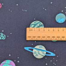Load image into Gallery viewer, Close up flat lay of 100% cotton flannelette from Art Gallery Fabrics  with a pattern of colourful planets and stars on a navy base, with ruler included for scale, available at Minerva's Bower