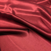 Load image into Gallery viewer, A close-up of a red viscose twill satin fabric surface, our Prom Viscose in Claret. Available at Minerva's Bower. Fabric draped to show how it handles