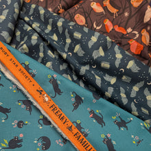 Load image into Gallery viewer, Pattern of black cats with flowers on a teal cotton Ruby Star Society fabric background. Made in Japan. Available at Minerva's Bower. Fabric draped to show how it handles. Collection of fabric bolts shown