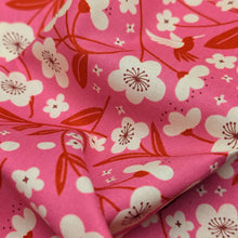 Load image into Gallery viewer, Floral pattern with red and white flowers on a pink cotton background. Made in Japan. Available at Minerva's Bower. Fabric draped to show how it handles
