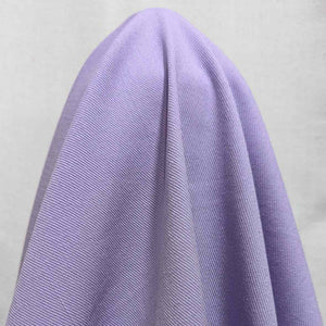 Flat lay of Sonnor stretch cotton Twill in lilac. Available at Minerva's Bower. Fabric is draped to show how it handles 