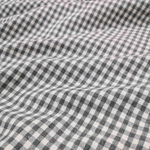 Flat lay of Spencer cotton linen check in grey. Available at Minerva's Bower. Fabric draped to show how it handles