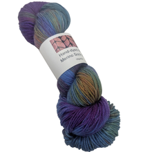 Load image into Gallery viewer, Purple and green Multicolored skein of merino sock yarn with a label on a white background