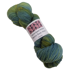 Load image into Gallery viewer, Green toned Hand-dyed merino sock yarn skein with a label on a white background