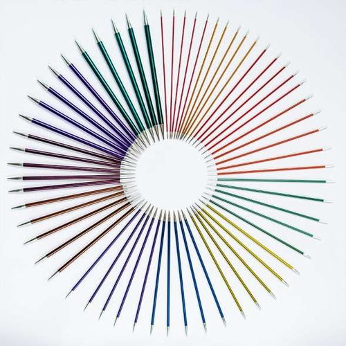 Set of colorful double pointed needles arranged in a circular pattern on a white background