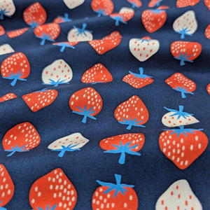 Flat lay of pure cotton, strawberries, by ruby star society. Made in Japan. Available at Minerva's Bower. Fabric draped to show how it handles