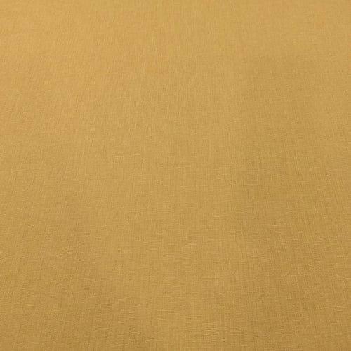 Flat lay of pure linen in a mustard colour. Available at Minerva's Bower