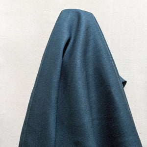 Flat lay of pure flax linen in petrol. Available at Minerva's Bower. Fabric draped to show how the fabric handles