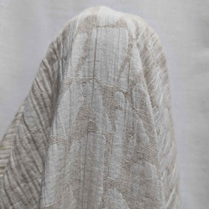 Textured cream muno jacquard fabric with a subtle pattern on a plain background. Available at Minerva's Bower