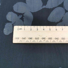 Load image into Gallery viewer, Liana is a drapey, lightweight, pure cotton voile, with the silhouette of foliage as a grey contrast on black background. Available at Minerva&#39;s Bower. Image includes a ruler for scale