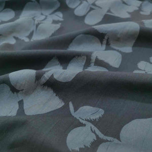 Liana is a drapey, lightweight, pure cotton voile, with the silhouette of foliage as a grey contrast on black background. Available at Minerva's Bower. Fabric is draped across bench