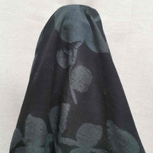 Load image into Gallery viewer, Liana is a drapey, lightweight, pure cotton voile, with the silhouette of foliage as a grey contrast on black background. Available at Minerva&#39;s Bower. Fabric is draped over roll